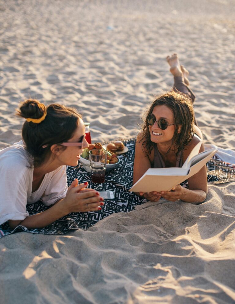 Dos amigas descansando en la arena de la playa